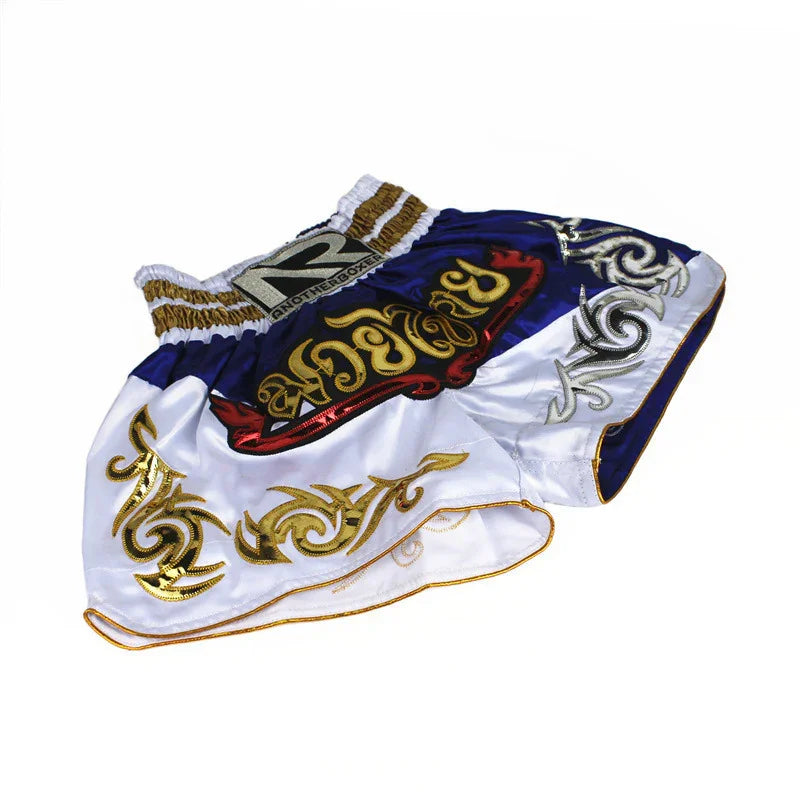 White and blue Muay Thai boxing shorts with gold embroidery and bold lettering