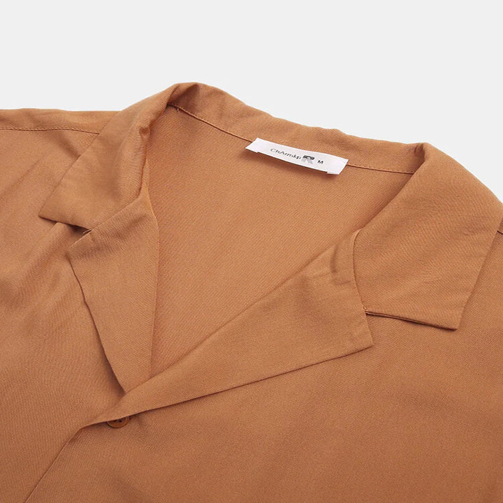 Close-up of a brown shirt collar with a folded lapel and visible brand label on a white background