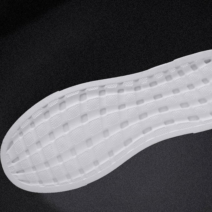 Close-up of white cushioned shoe insole with textured grid pattern on black background