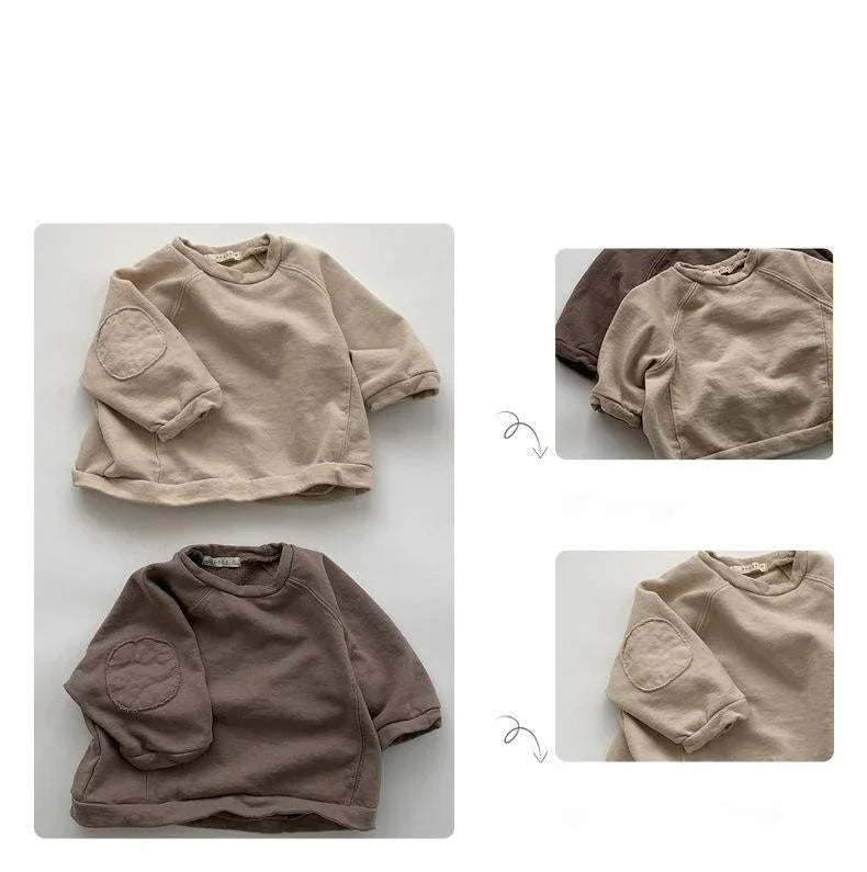 Beige and brown baby sweatshirts with elbow patches laid flat on white background
