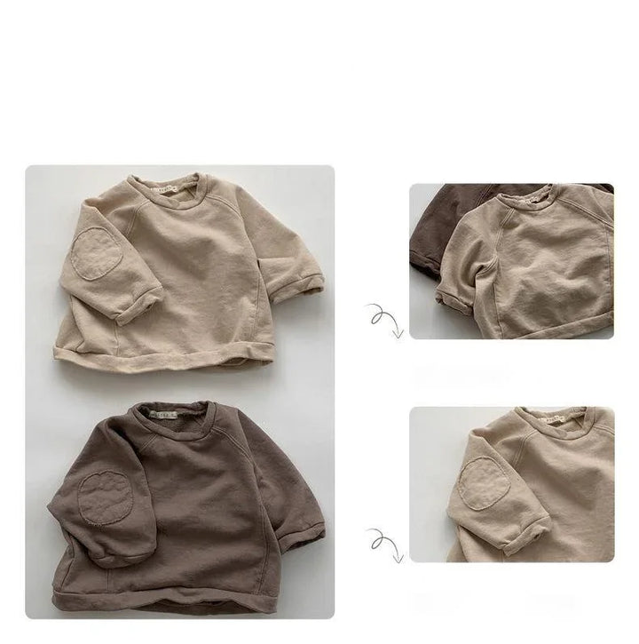 Beige and brown baby sweatshirts with elbow patches laid flat on white background