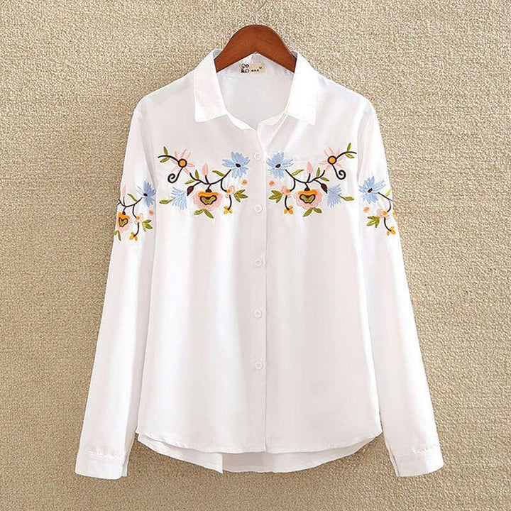White button-up blouse with long sleeves and blue floral embroidery on chest and sleeves