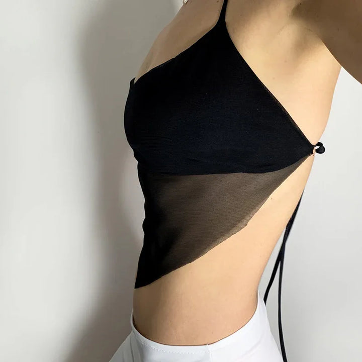 Side view of a woman wearing a black mesh backless crop top paired with white pants