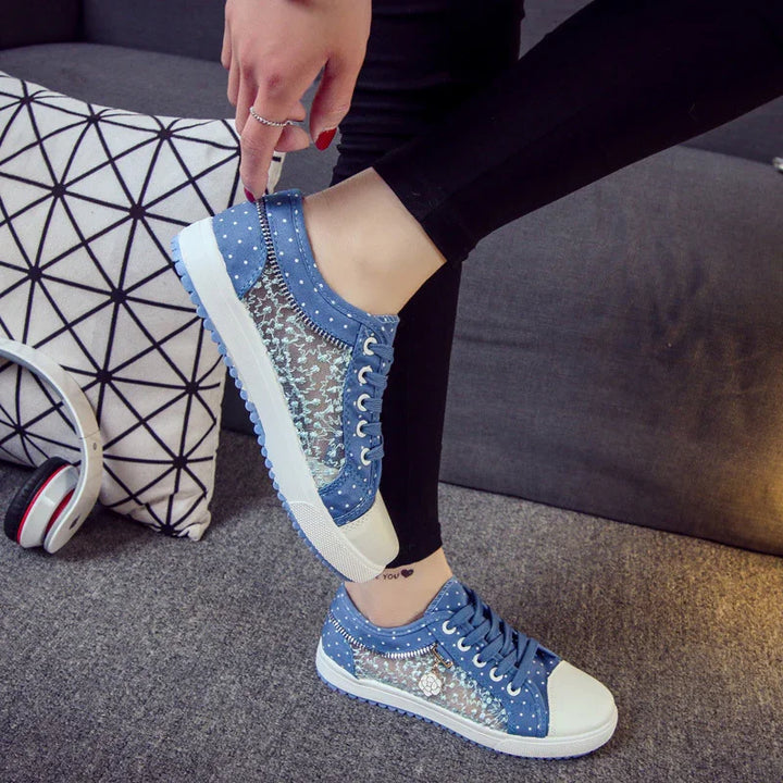 Blue lace sneakers with polka dot accents worn by person sitting on gray sofa