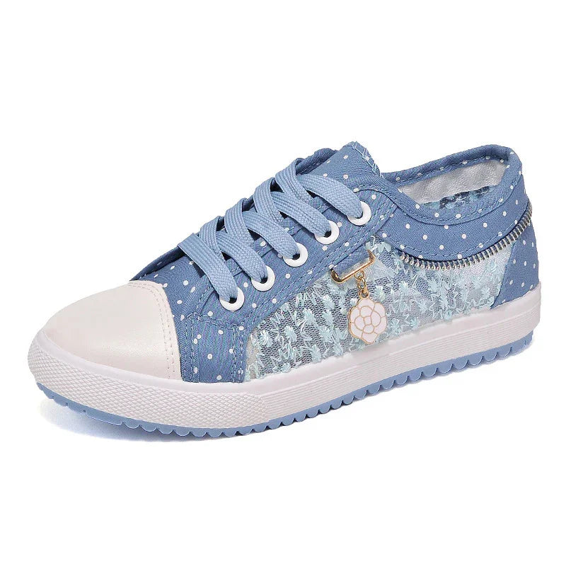 Blue and white polka dot sneaker with white toe cap, lace-up design, lace side panel, and flower charm