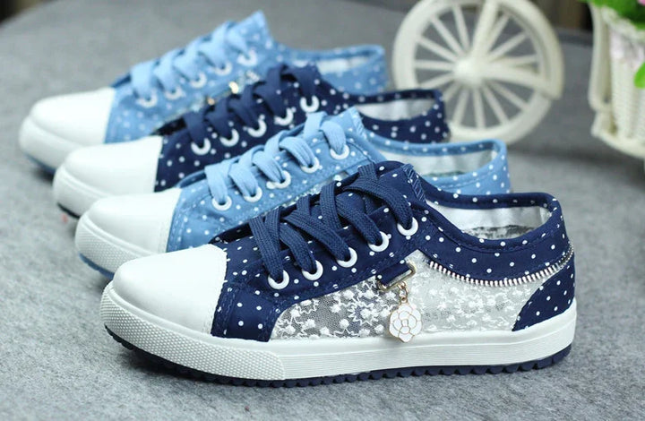 Polka dot lace sneakers in navy and light blue, featuring white rubber toes and decorative charm on gray surface