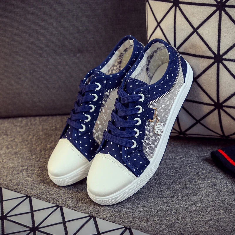 Navy blue polka dot casual sneakers with white toe cap and lace-up design on gray carpet
