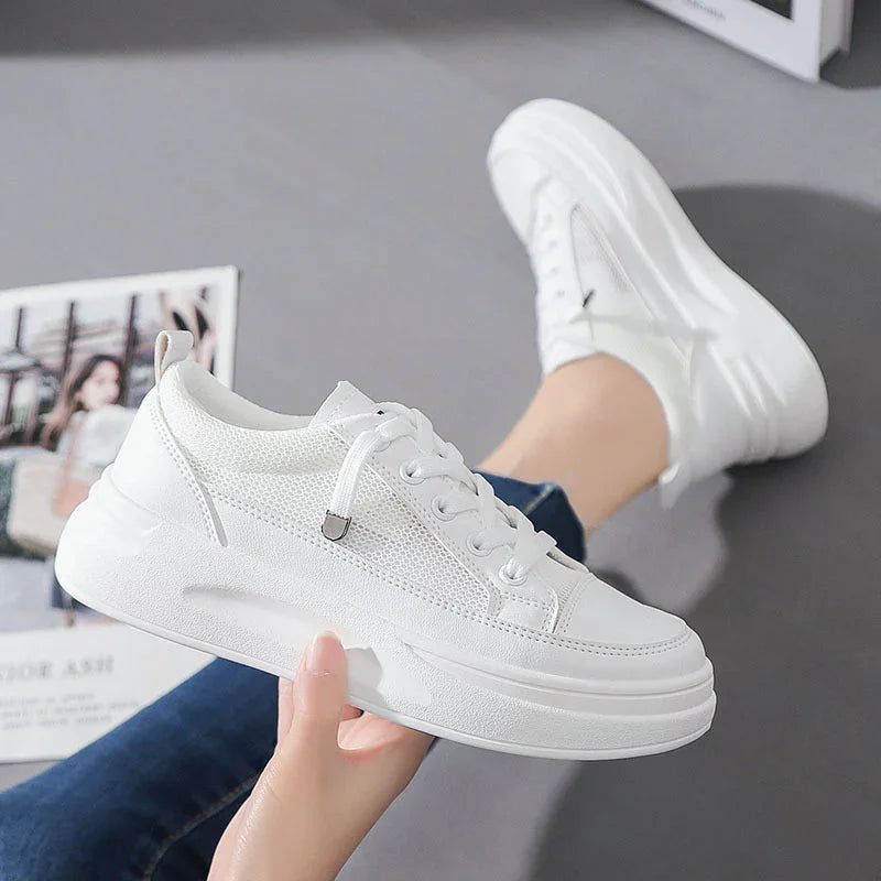 White casual sneakers with thick sole and mesh details worn with blue jeans on gray floor