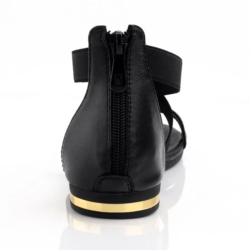 Rear view of black leather sandal with zipper and gold stripe on flat heel
