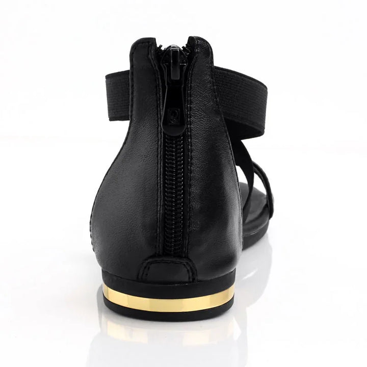 Rear view of black leather sandal with zipper and gold stripe on flat heel