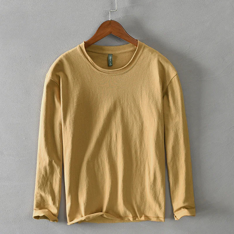 Beige long-sleeve cotton shirt on wooden hanger against gray wall