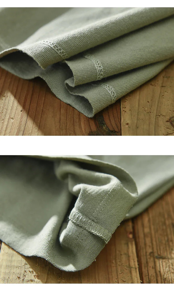 Close-up of olive green fabric with detailed stitching on wooden surface