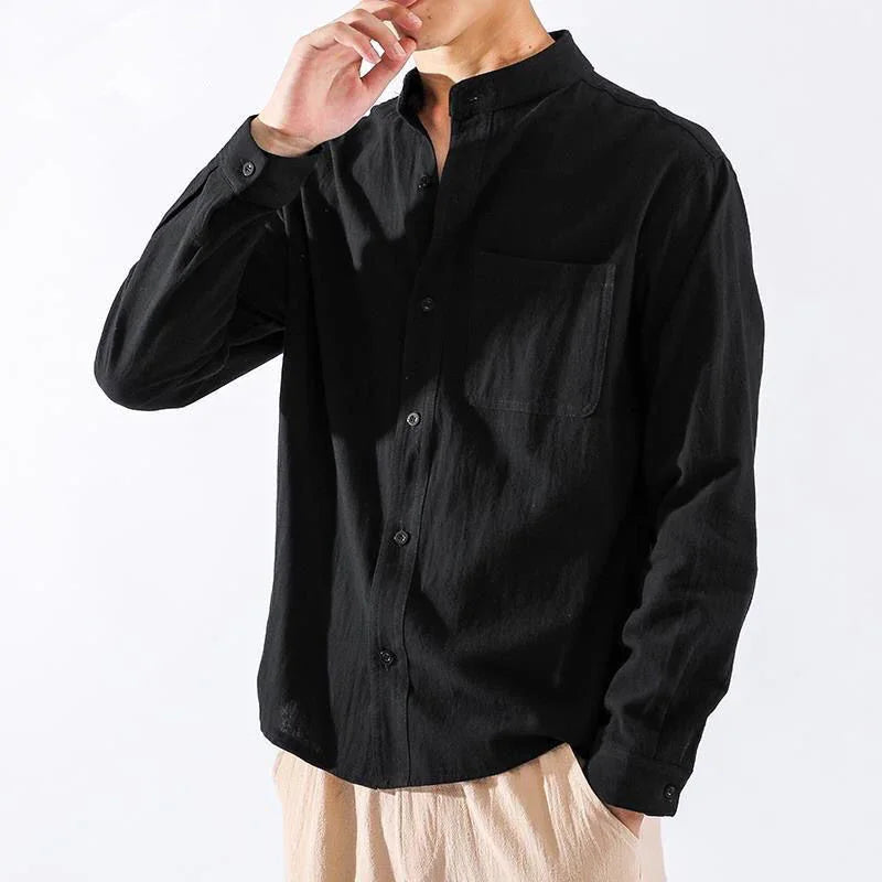 Man wearing black mandarin collar long sleeve shirt and beige pants on white background