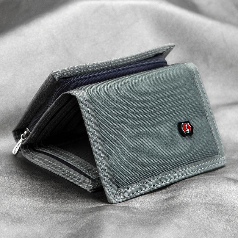 Gray fabric wallet with a small emblem, partially open, placed on a matching gray surface