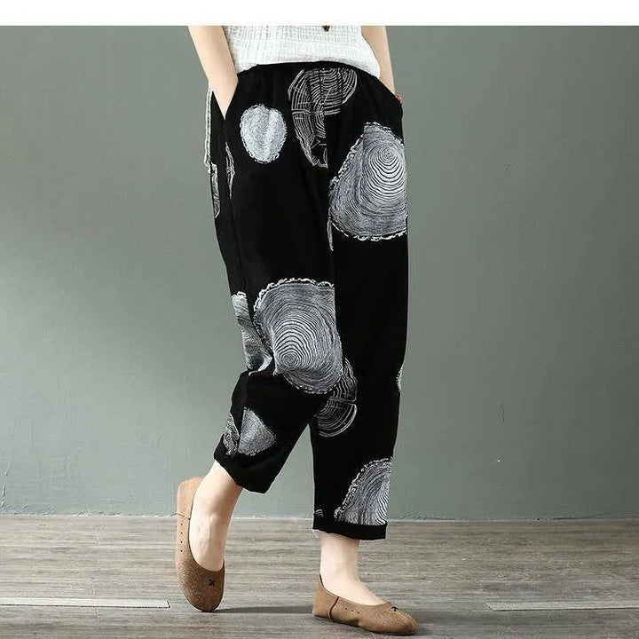 Casual black pants with white circular tree ring pattern worn with brown flats on wooden floor