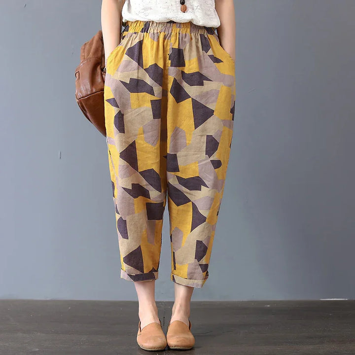 Woman wearing loose-fitting cropped pants with geometric yellow, brown, and beige pattern and rolled cuffs