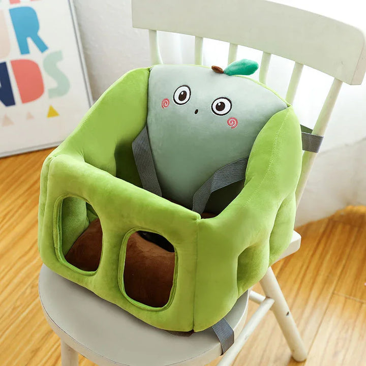 Soft green plush baby booster seat with cute fruit face design on white chair