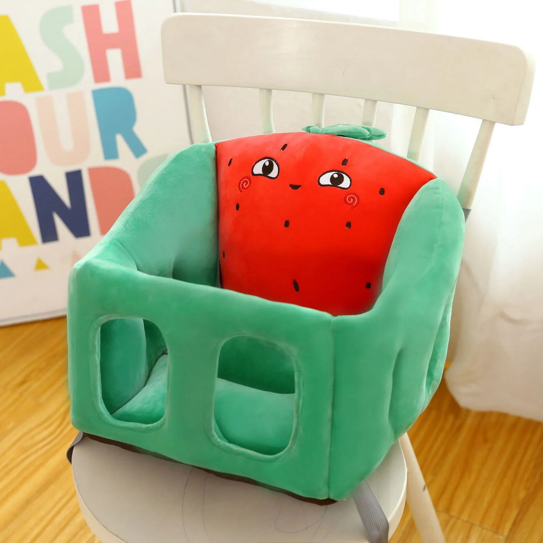 Green baby booster seat with a cute smiling red strawberry cushion on a white wooden chair