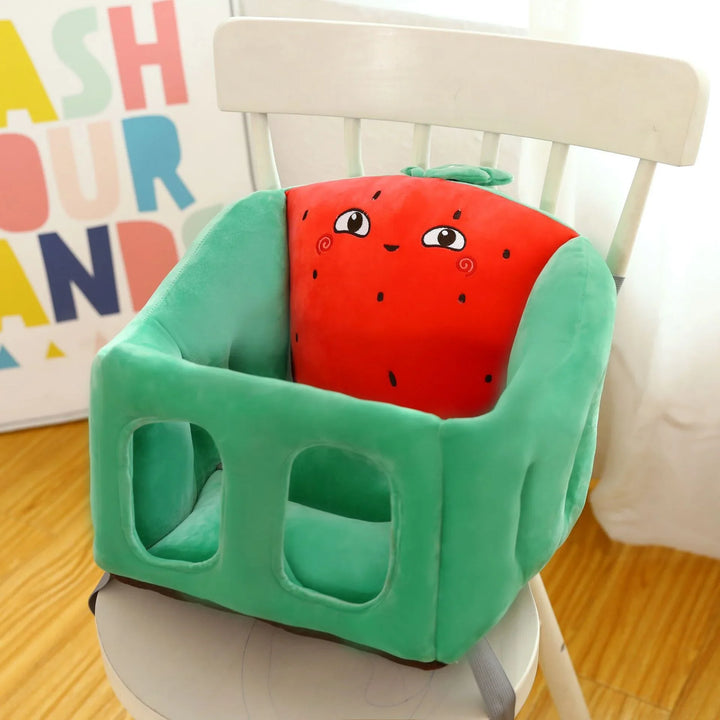 Green baby booster seat with a cute smiling red strawberry cushion on a white wooden chair