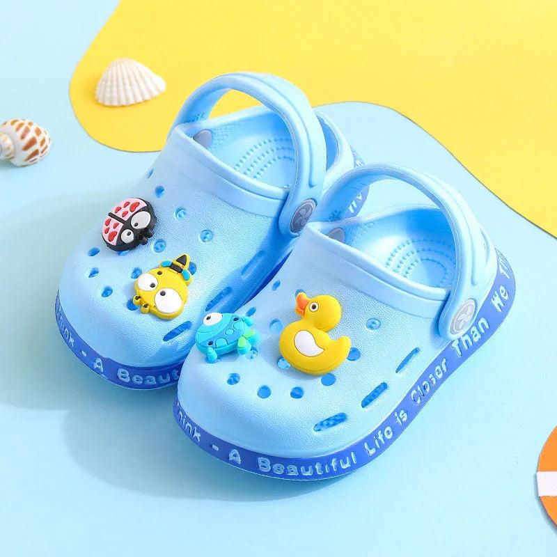 Light blue kids clogs with animal-shaped charms including ladybug, duck, and frog on a colorful background
