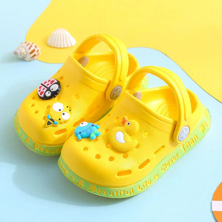 Bright yellow kids' clogs with cartoon bug and duck charms on a blue and yellow background
