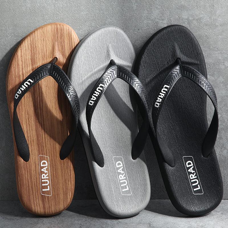 Three LURAD brand flip-flops in wood grain brown, gray, and black on a gray surface