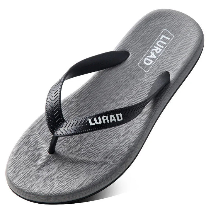 Gray LURAD flip flop sandal with textured black straps on white background