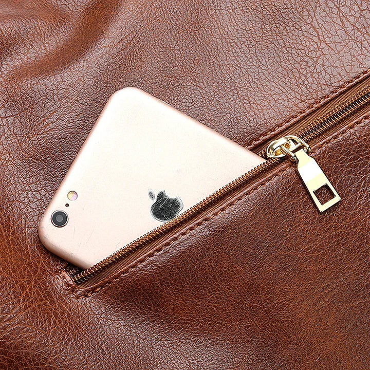 Gold iPhone partially inside a brown leather zippered pocket with visible zipper details