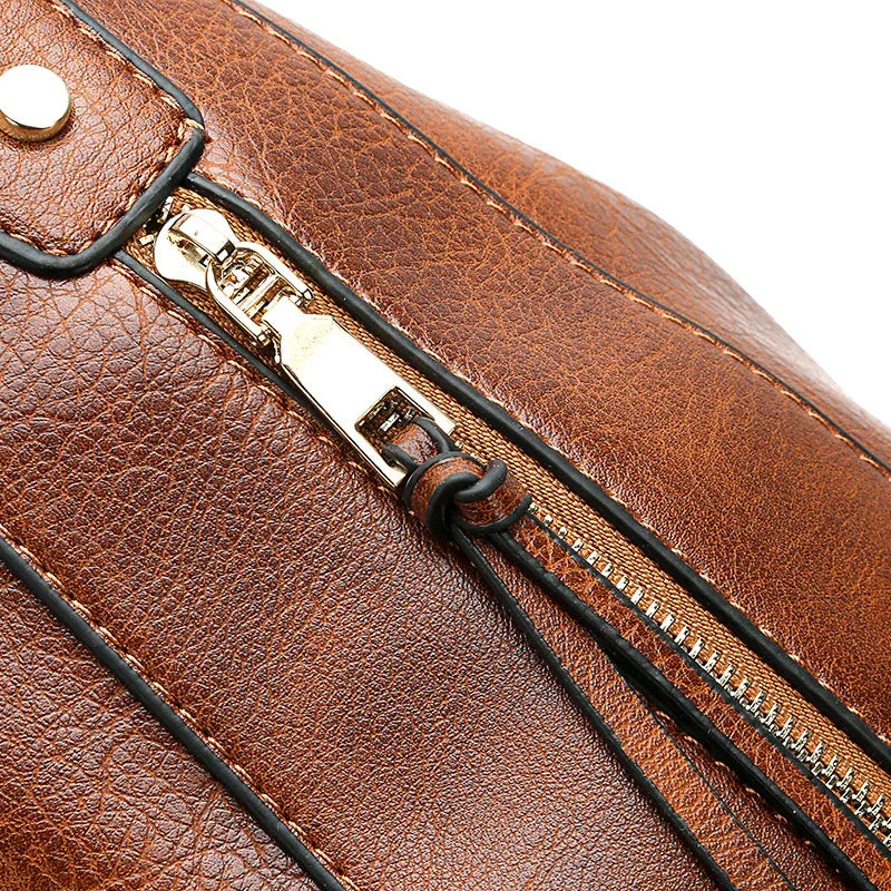 Close-up of brown leather bag with gold zipper and black trim detail