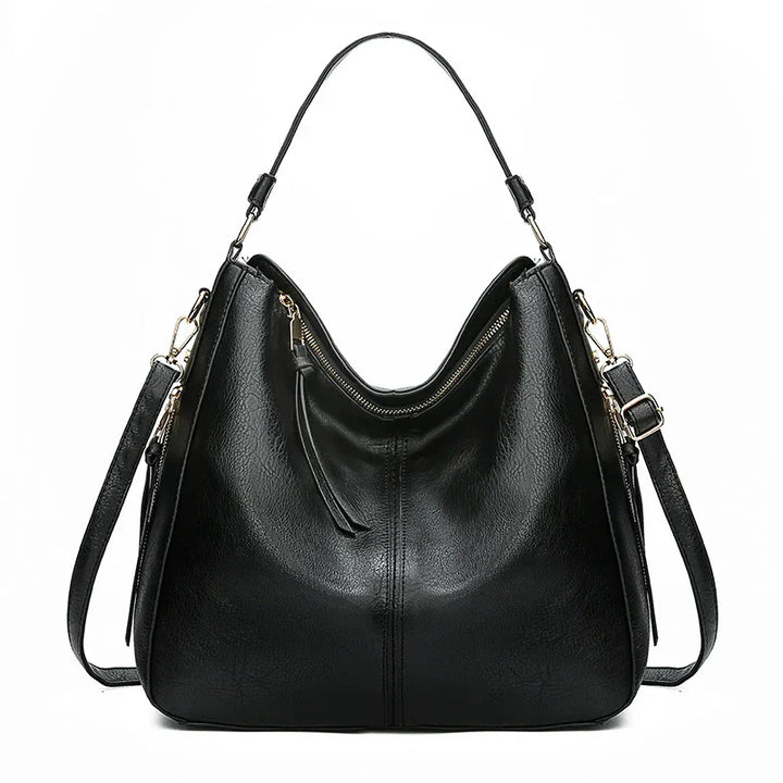 Black leather hobo handbag with gold zipper and detachable shoulder strap on white background
