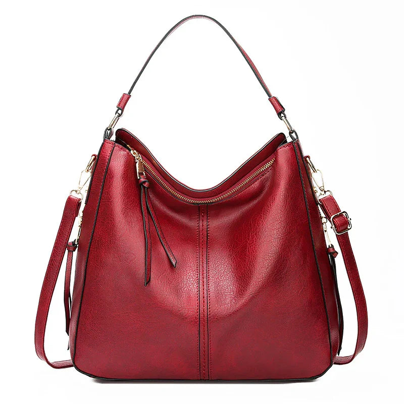 Red leather handbag with gold zipper, top handle, and detachable shoulder strap on white background