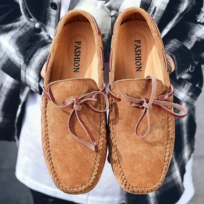 Pair of brown suede loafers with leather laces labeled Fashion held by person in plaid shirt