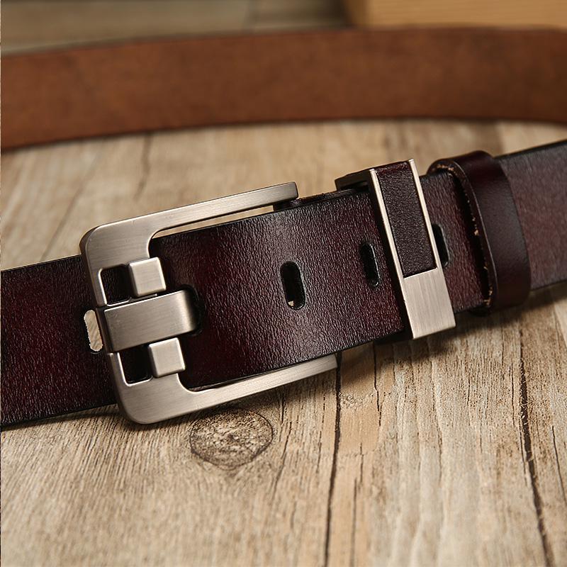 Close-up of dark brown leather belt with metal buckle on wooden surface