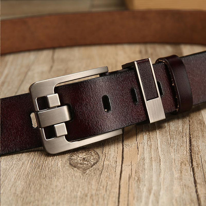 Close-up of dark brown leather belt with metal buckle on wooden surface
