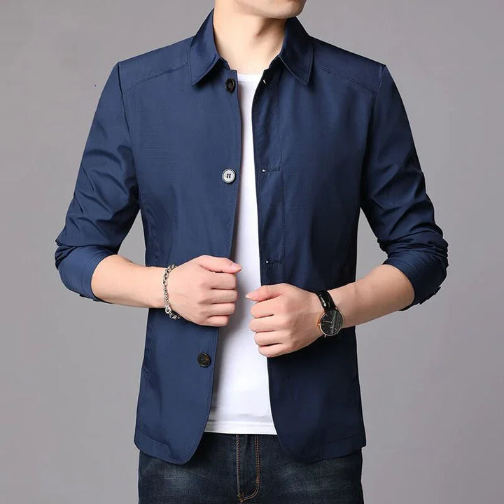 Man wearing navy blue button-up casual blazer with white t-shirt and dark jeans, showing watch and bracelet