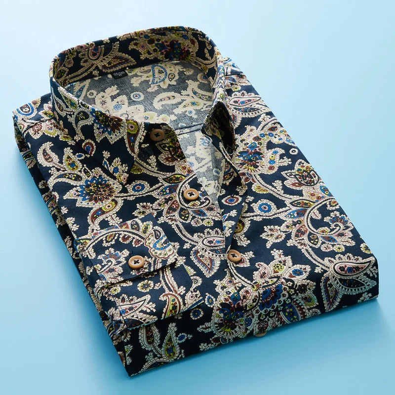 Folded men's paisley print dress shirt with wooden buttons on light blue background