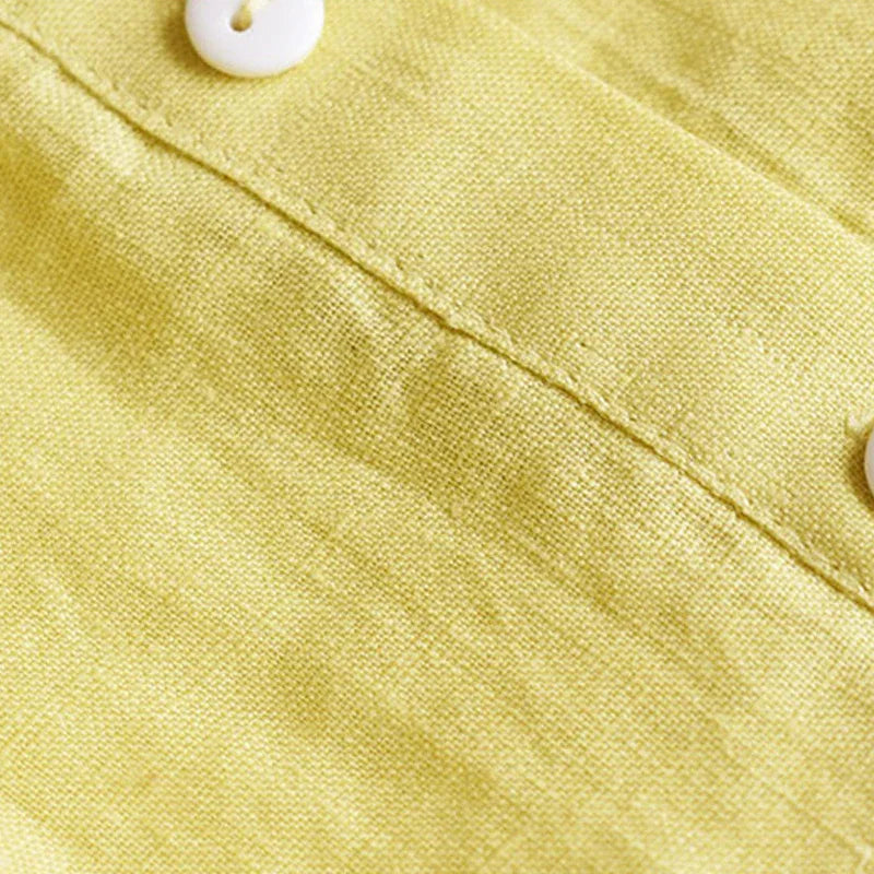 Close-up of yellow linen fabric with white buttons and visible stitching detail