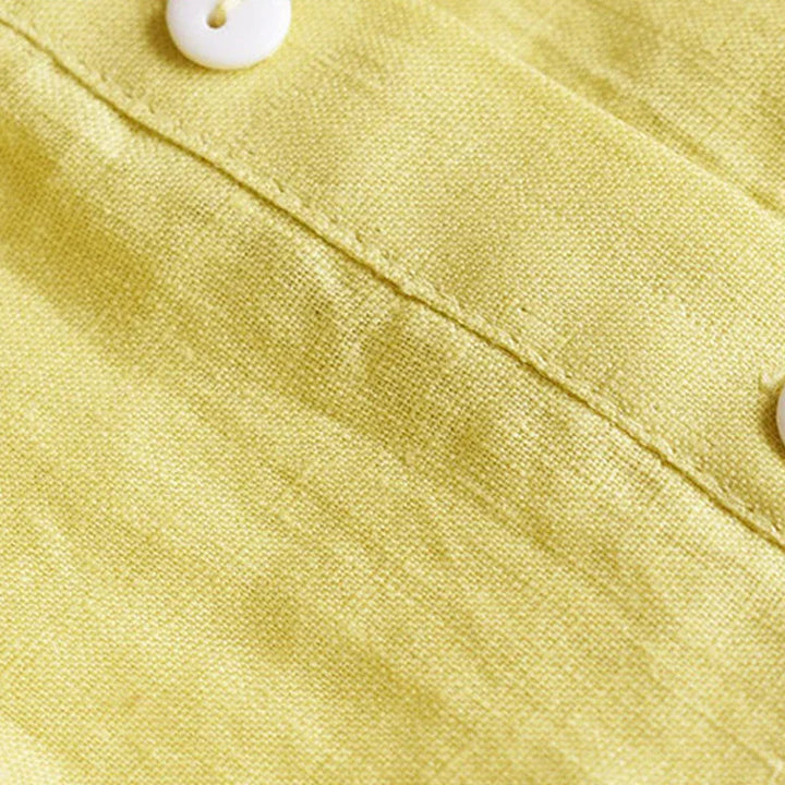 Close-up of yellow linen fabric with white buttons and visible stitching detail