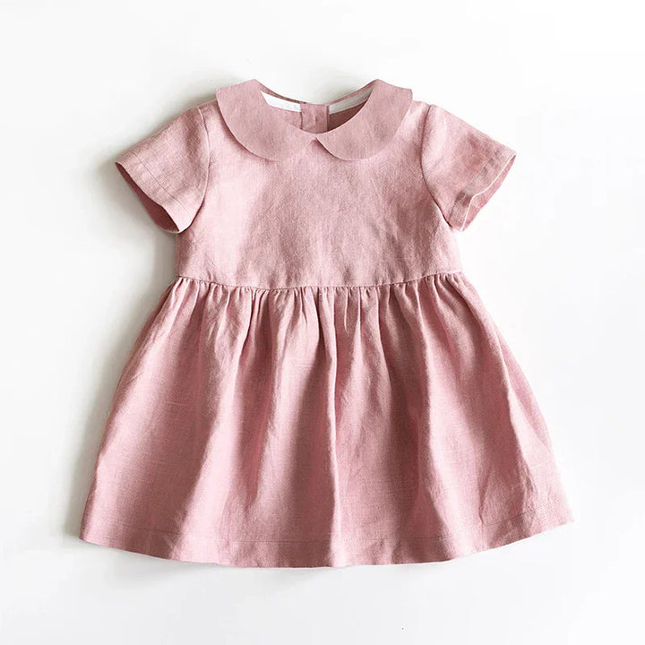 Pink short sleeve baby dress with Peter Pan collar made of soft linen fabric on white background