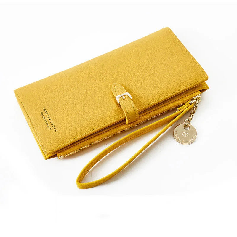 Yellow leather wristlet wallet with buckle strap and gold charm on white background