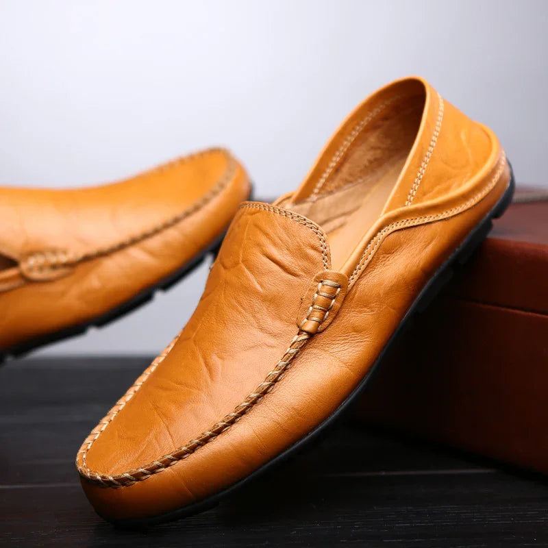 Pair of tan leather slip-on driving loafers with stitched detailing and black rubber soles