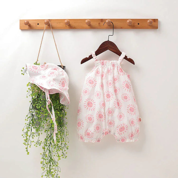Baby romper and matching sun hat with pink sun prints hanging on wooden hooks