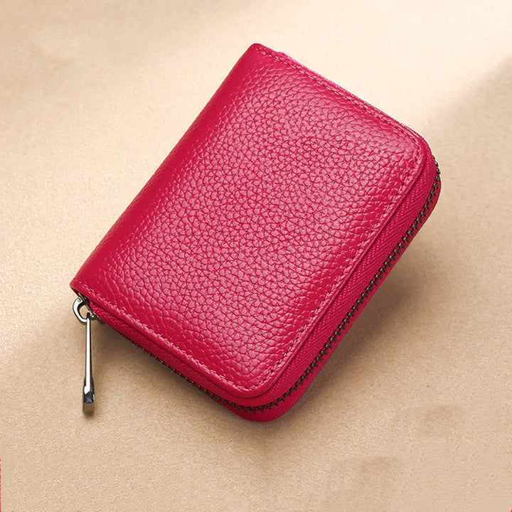Compact red leather zippered wallet with textured surface on beige background