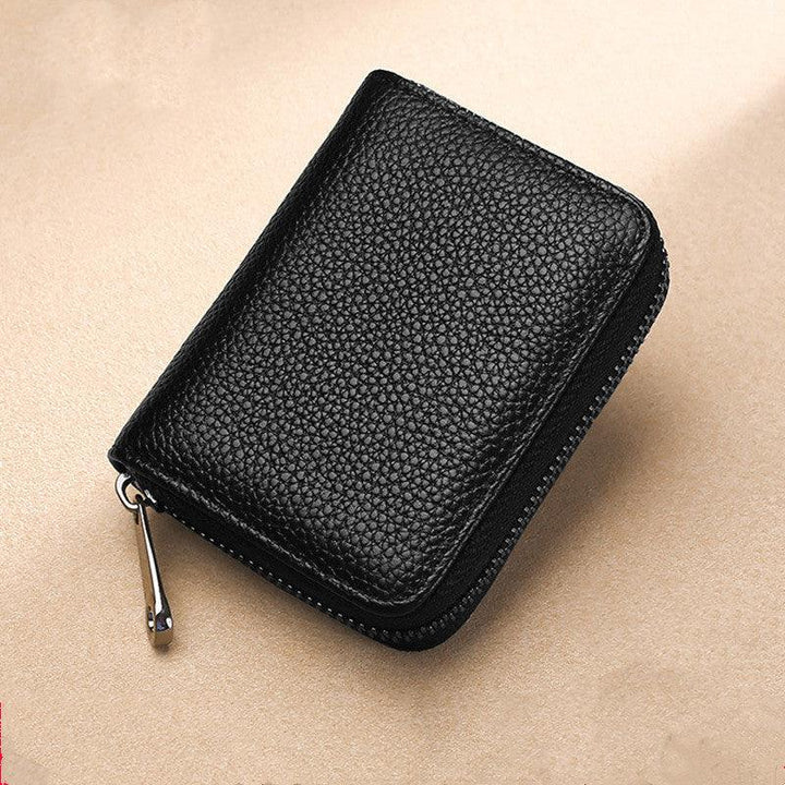 Black textured leather zippered wallet with silver zipper pull on beige background