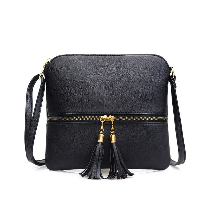 Black leather crossbody bag with gold zipper and tassel accents, adjustable strap