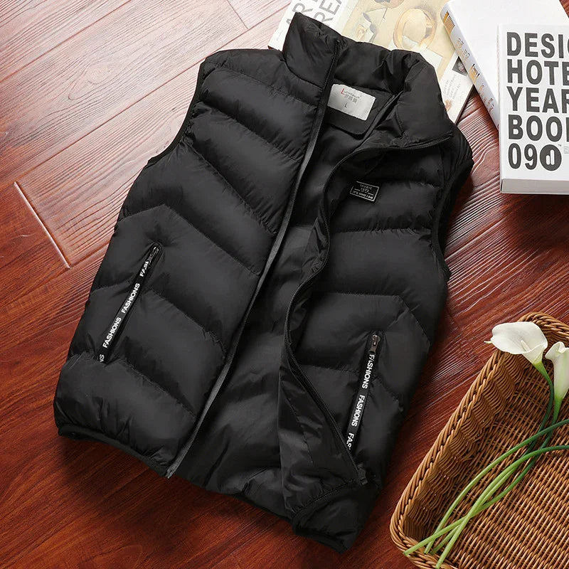 Black quilted sleeveless puffer vest with zippered pockets on wooden floor near design book and flowers