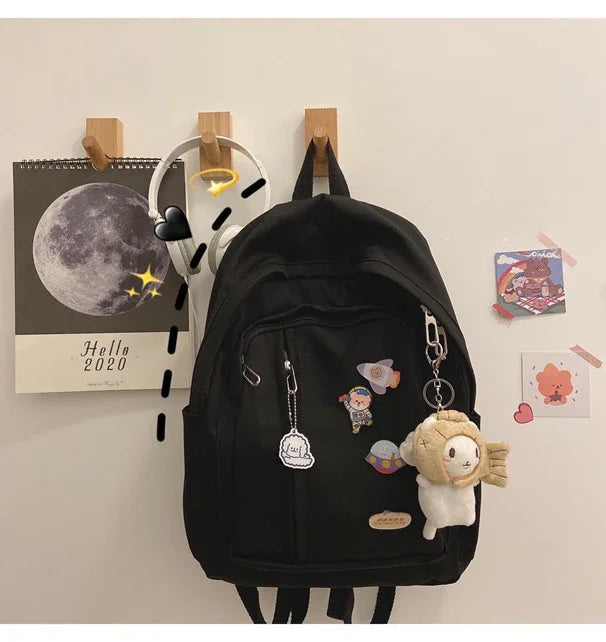 Black backpack with cute pins and plush keychain hanging on wall, moon calendar in background