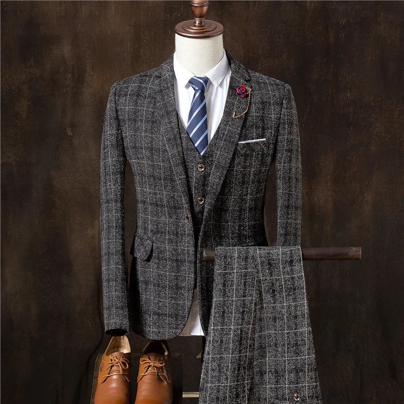 Men's grey checked three-piece suit with blue striped tie and brown leather shoes on mannequin