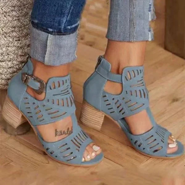 Blue cutout ankle strap sandals with wooden block heels worn with rolled-up denim jeans on wooden floor