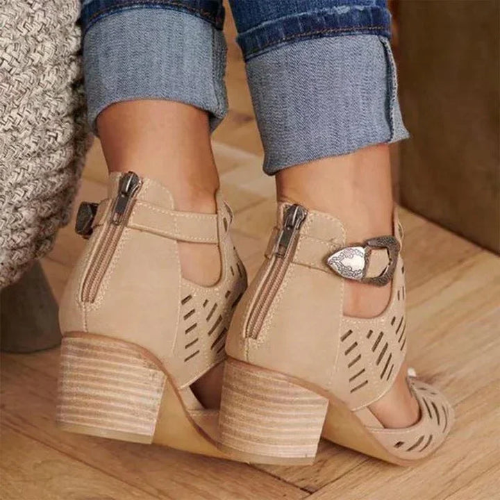 Beige suede block heel sandals with zipper and buckle, worn with rolled-up blue jeans on wooden floor